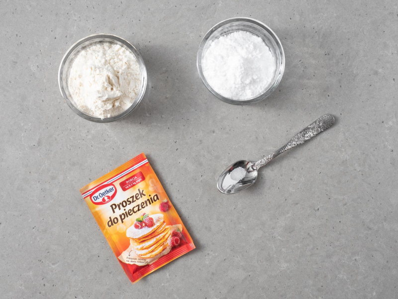 W małych miskach mąka pszenna i cukier puder. Obok proszek do pieczenia i łyżeczka z solą.