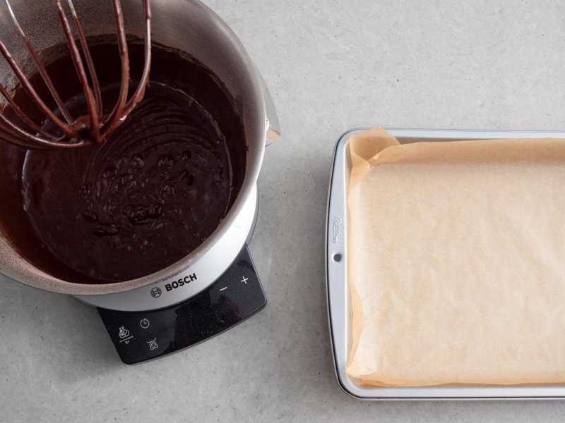w misie robota bosch przygotowane ciasto czekoladowe obok forma do pieczenia wyłożona papierem do pieczenia
