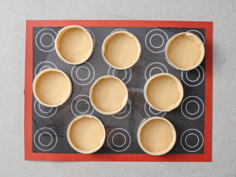 ranty perforowane na macie silikonowej wypełnione kruchym ciastem przed pieczeniem