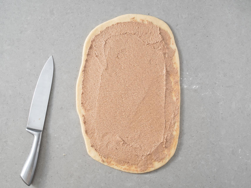 Rozłożona na placku drożdżowym masa cynamonowa.