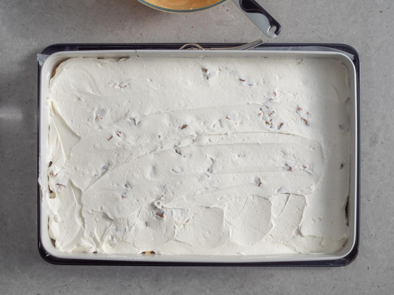 w blaszce ciasto posmarowane kremem śmietankowym z kawałkami krówek