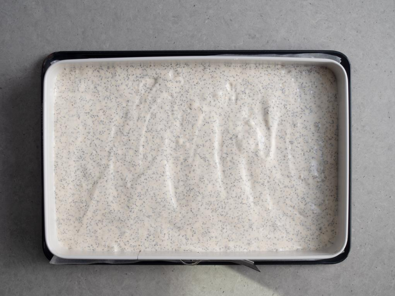 w dużej blaszce biszkopt makowy przed pieczeniem