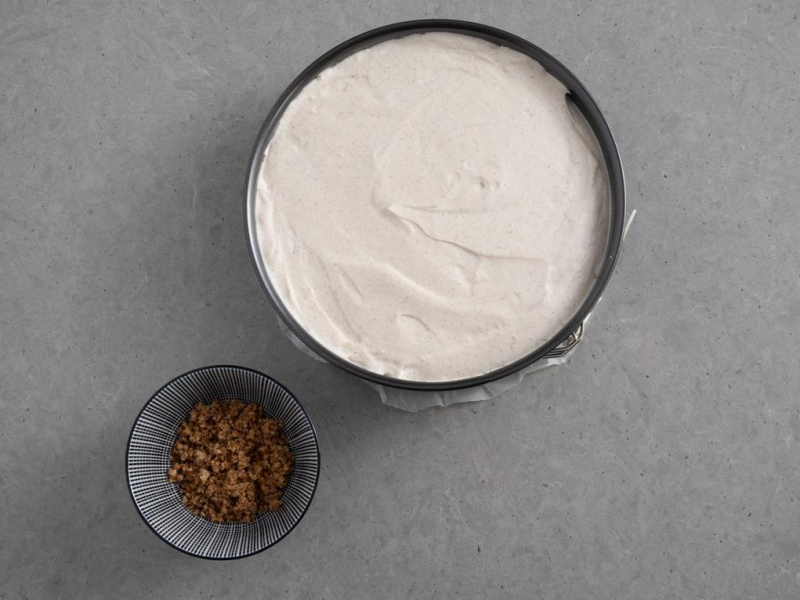 w tortownicy sernik cynamonowy obok miseczka z kruszonką orzechową