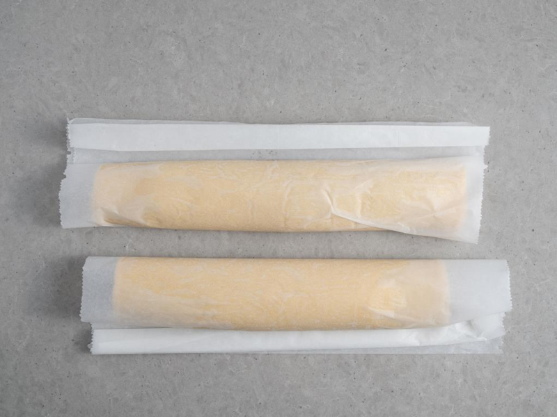 na blacie dwa zawijane makowce w papierze do pieczenia