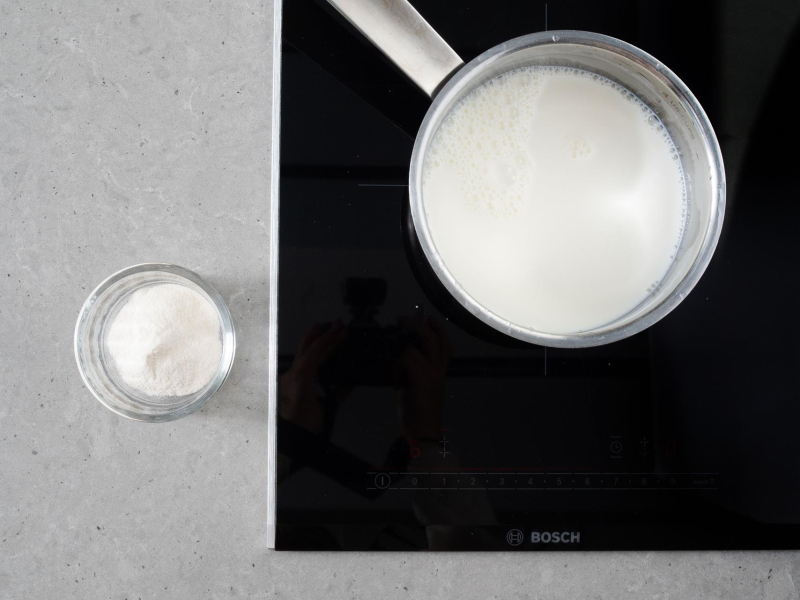 W garnku śmietanka na płycie kuchennej. Obok  agar w miseczce.