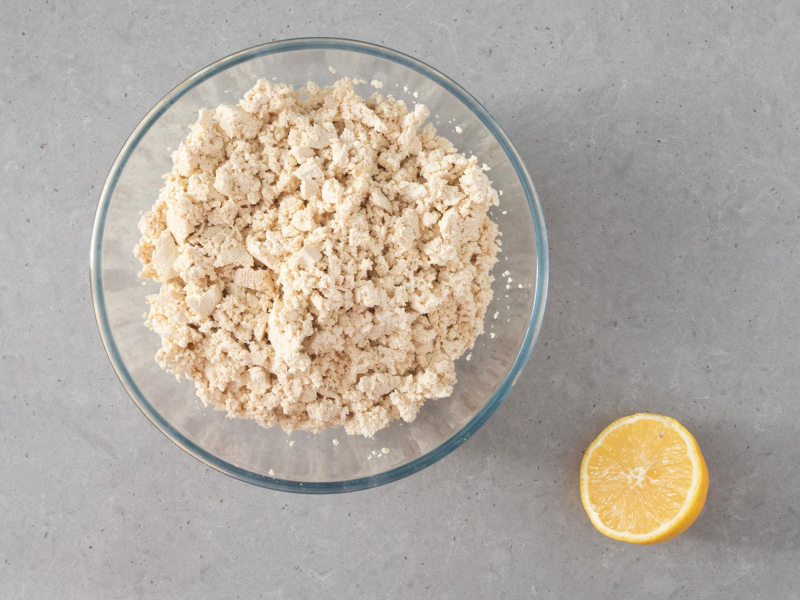 W misce pokruszone tofu. Obok przekrojona cytryna.