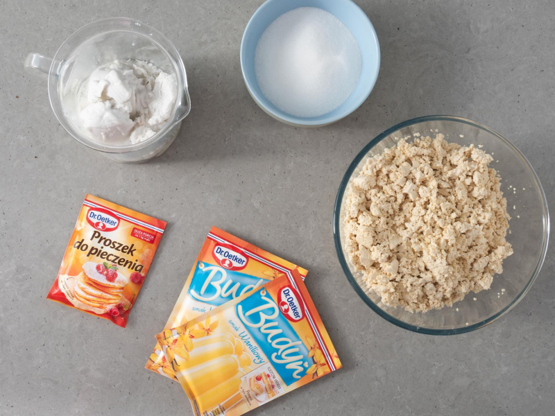 W misie pokruszone tofu. Obok budynie, proszek do pieczenia. Oraz cukier w misce i mleczko kokosowe.