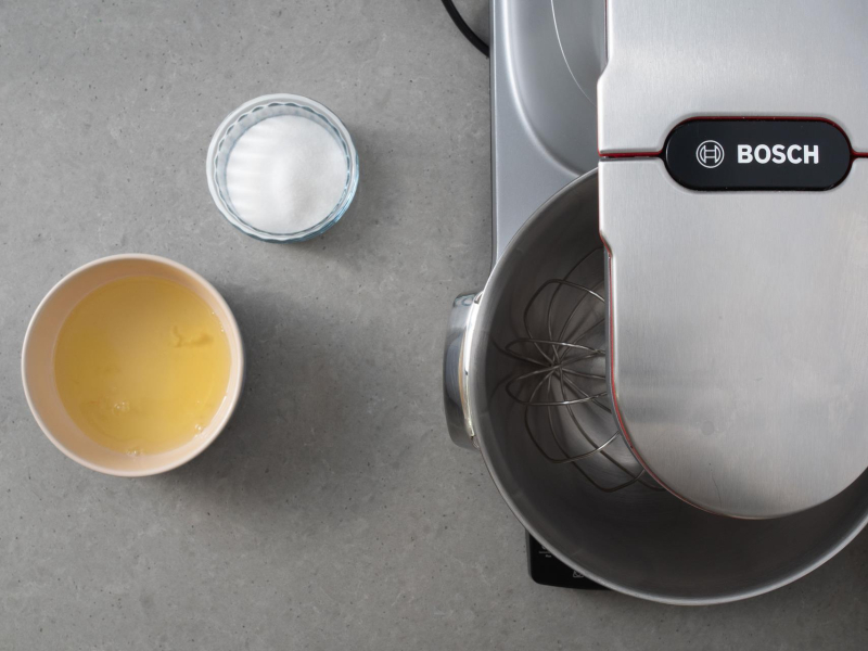 Na blacie kuchennym robot firmy Bosch, a w miseczkach cukier oraz białka jaj.