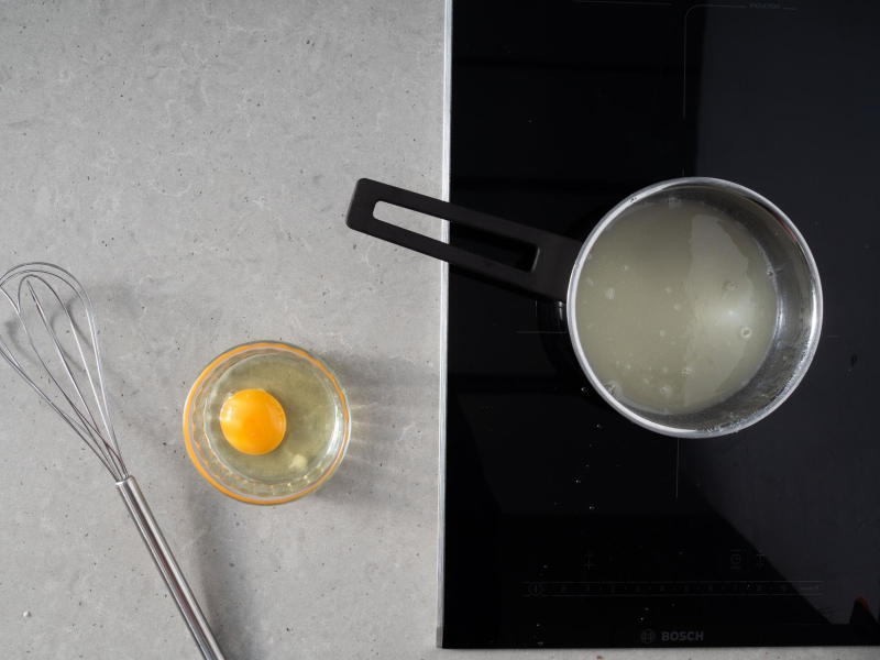 Na blacie kuchennym rózga oraz jajko w miseczce.