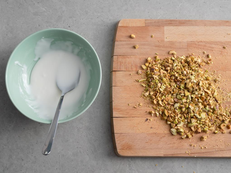 w miseczce wymieszany lukier i na drewnianej desce posiekane pistacje