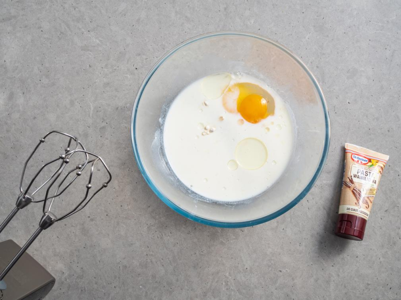 w szklanej misce mleko, jajko obok pasta z wanilii Dr. Oetkera