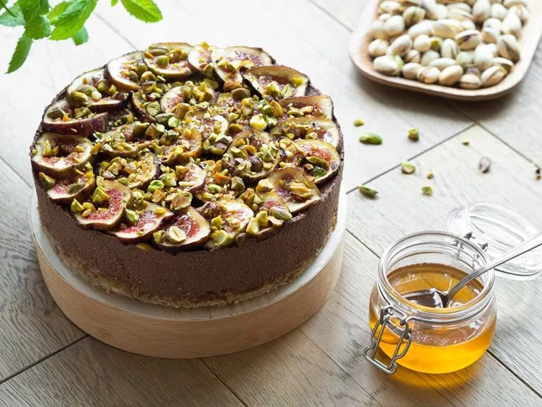 czekoladowy tofurnik z figami, polany syropem z agawy i posypany pistacjami