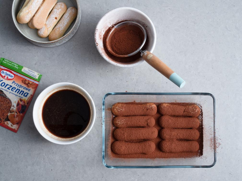 w naczyniu warstwa biszkoptów posypana kakao