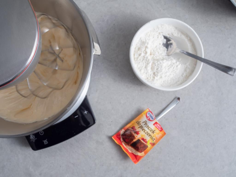 w robocie kuchennym bosch ucierane żółtka z cukrem, na blacie mąka i proszek do pieczenia Dr. Oetkera