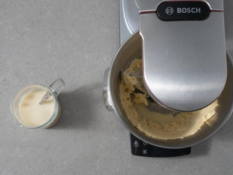 Ucieranie margaryny z cukrem robotem kuchennym. Obok napój sojowy.