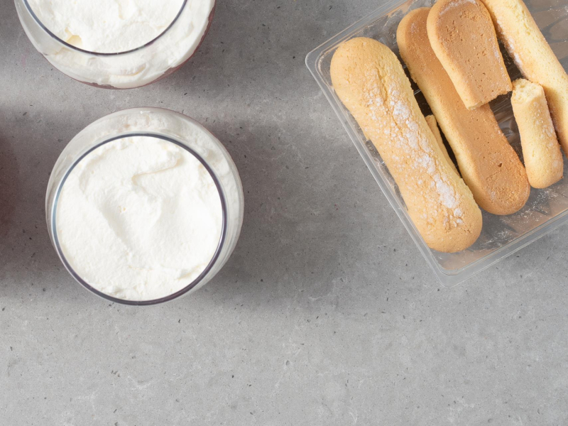 Pucharki z na艂o偶on膮 bit膮 艣mietan膮. Osobno w pojemniku pod艂u偶ne biszkopty,