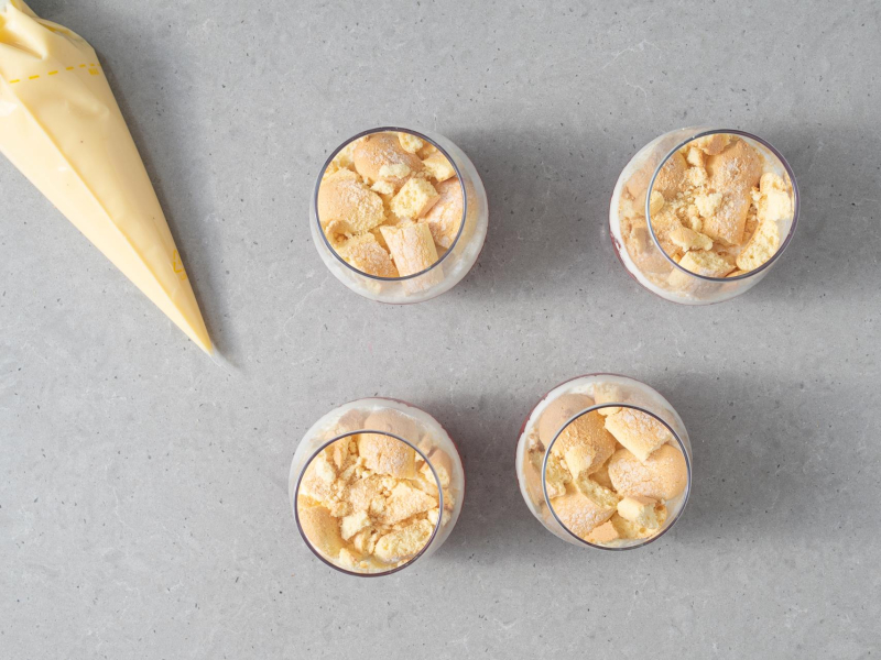 Sos waniliowy w r臋kawie cukierniczym. Obok 4 pucharki  deserowe z biszkoptami.