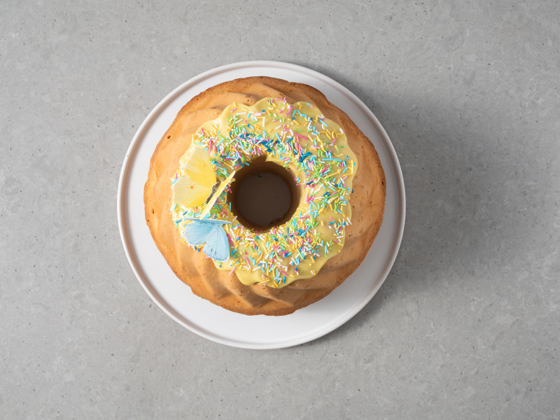 Udekorowana babka wielkanocna z lukrem, posypką i motylkami z opłatka waflowego.