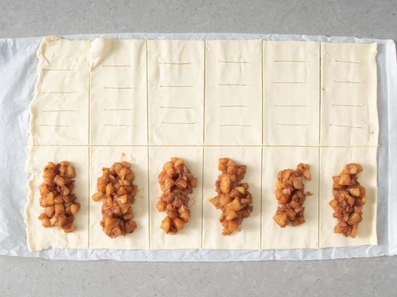 Ułożone nadzienie z jabłek na kawałkach ciasta francuskiego.