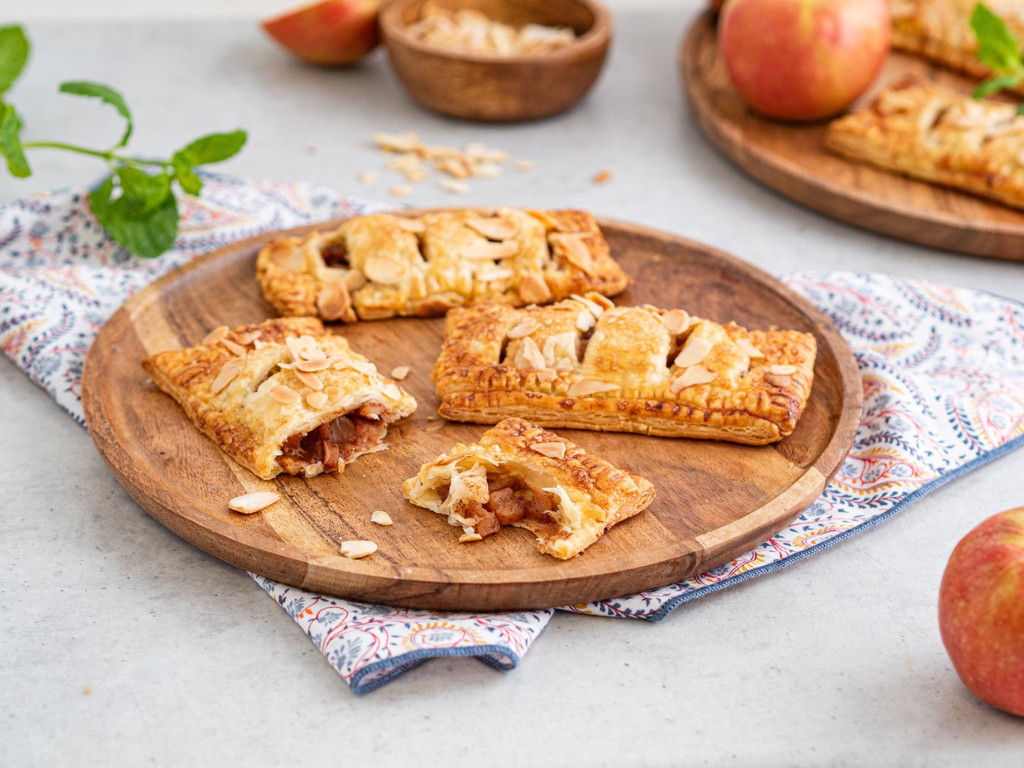 Ciastka francuskie z jabłkami posypane płatkami migdałów na drewnianej tacy - Przepis Wszystkiego Słodkiego