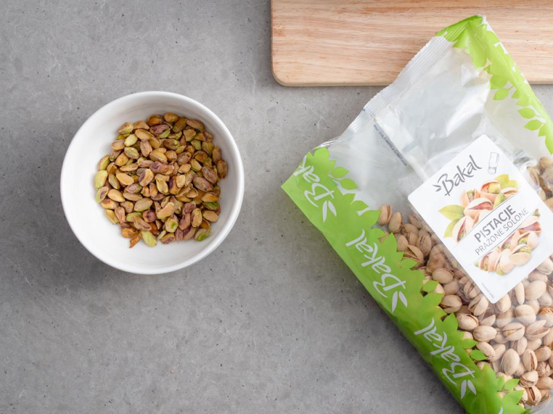 w miseczce obrane pistacje, obok opakowanie pistacji Bakal