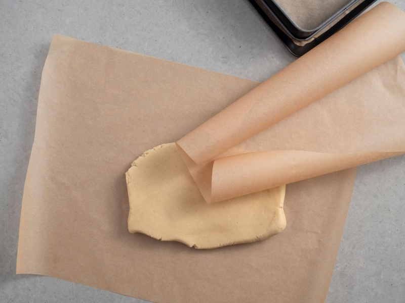 kruche ciasto pomiędzy arkuszami papieru do pieczenia