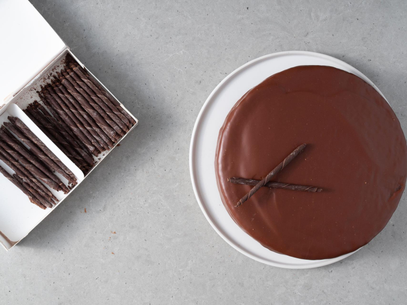 Gotowy tort Sachera udekorowany ołówkami z czekolady.