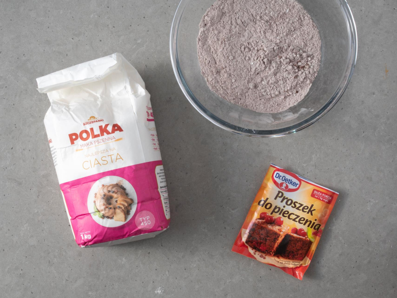 Na blacie opakowanie mąki, proszek do pieczenia oraz wymieszane suche składniki do przygotowania tortu Sachera.