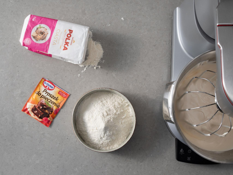 Na blacie kuchennym mąka pszenna oraz opakowanie proszku do pieczenia.