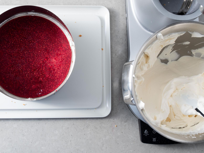W misie miksera krem śmietankowy z mascarpone. Obok żelka malinowa na cieście.
