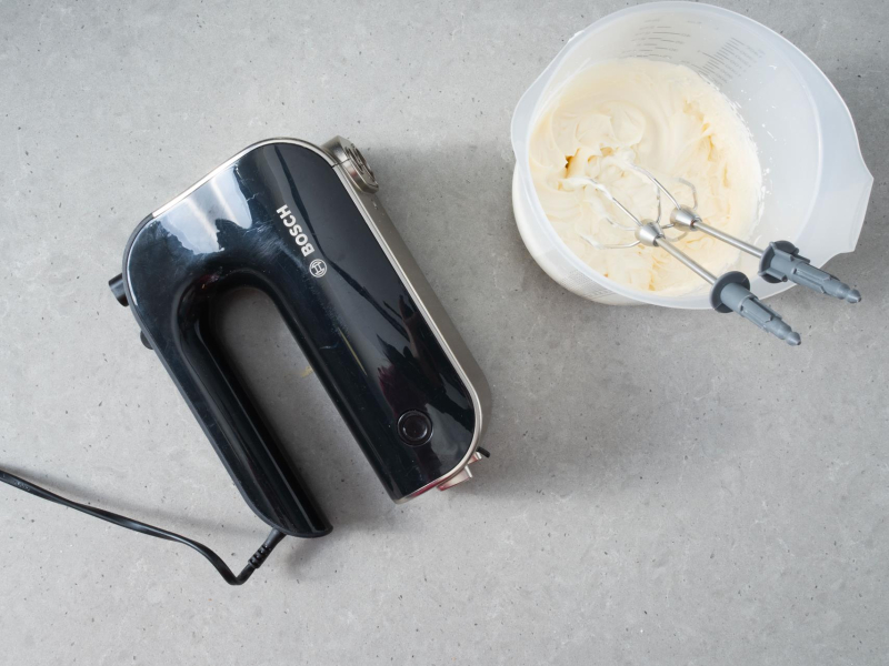 W misce ubita śmietanka. Obok mikser ręczny.