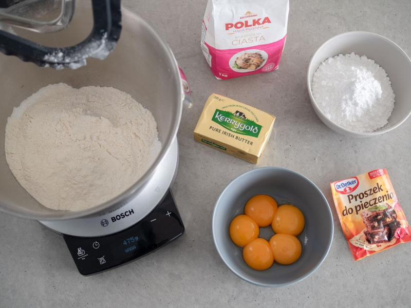 w misce robota bosch mąka Polka, na blacie masło Kerrygold, cukier puder i proszek do pieczenia