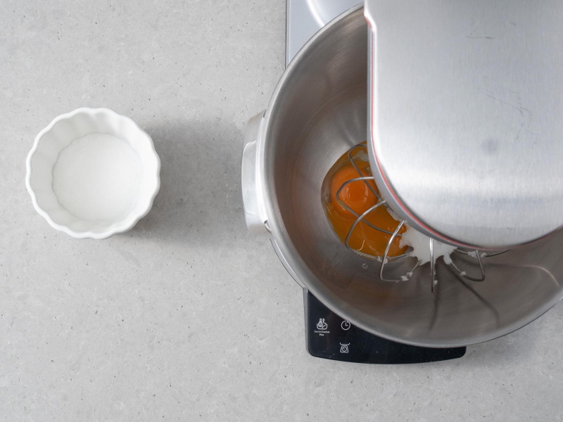 W miseczce cukier. Obok ubieranie żółtek z cukrem.