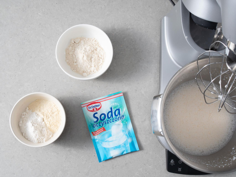 Na blacie kuchennym opakowanie sody oczyszczonej Dr. Oetker Obok mąki bezglutenowe do przygotowania gofrów bezglutenowych.