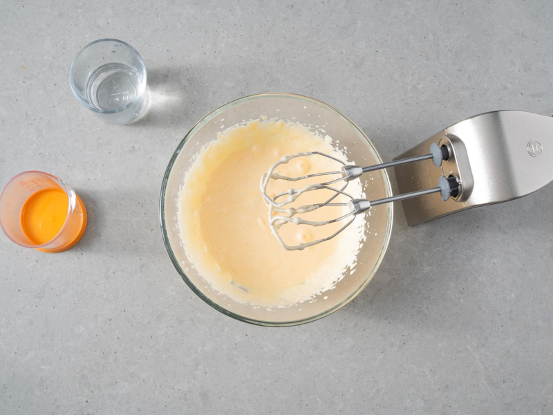 W misie utarte żółtka z cukrem. Obok olej oraz woda.