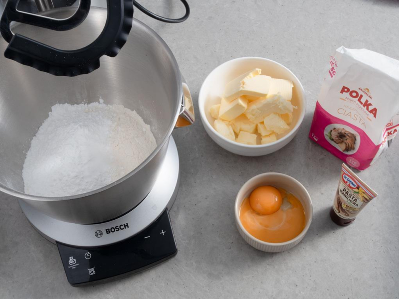 składniki na kruche ciasto z budyniem, w miseczce mąka Polka, pokrojone masło, żółtka i pasta z wanilii Dr. Oetkera