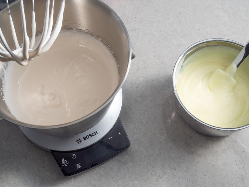 w misie robota bosch utarte jajka z cukrem pudrem obok ugotowany budyń w garnku