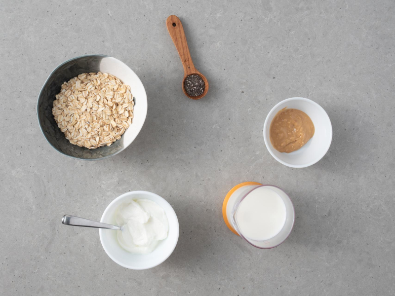 Miseczki z p艂atkami owsianymi, jogurtem, mlekiem, nasionami chia i mas艂em orzechowym.