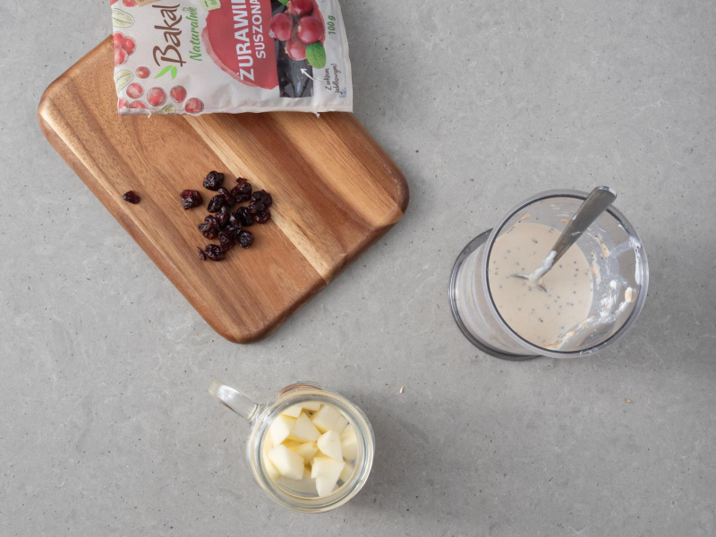 Na desce suszona 偶urawina. Obok s艂oiczek z kawa艂kami jab艂ek i mieszanka na owsiank臋 nocn膮.