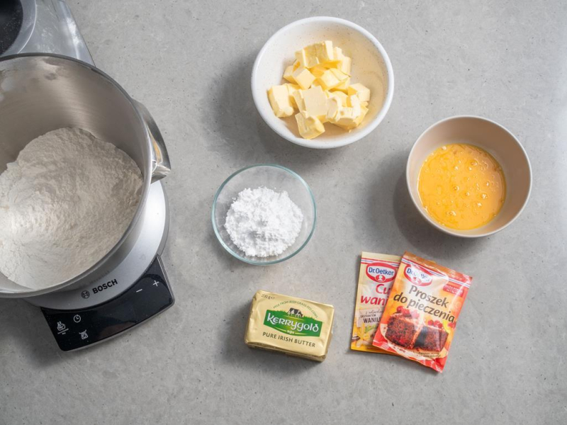 W misie mąka psklasycznego Lurpakzenna. Obok miseczka z jajkami, masłem oraz opakowanie masła Lurpak i proszek do pieczenia Dr. Oetkera.
