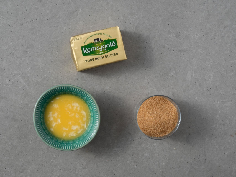 w miseczce rozpuszczone masło Kerrygold obok w szklance brązowy cukier