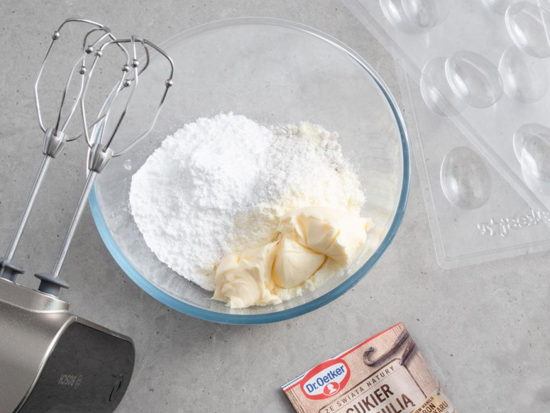w misce szklanej składniki na jajka z mleka w proszku, obok masło cukier z wanilią Dr. Oetkera