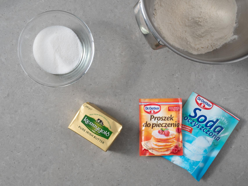 W misie miksera mąka. Obok soda oczyszczona Dr. Oetkera, proszek do pieczenia, oraz masło.