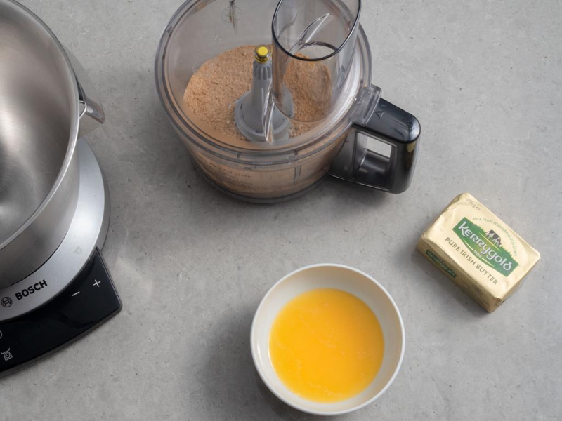 pokruszone ciasteczka w malakserze, w miseczce rozpuszczone mas艂o Kerrygold