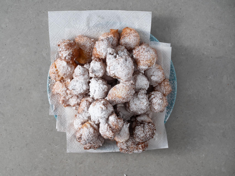 Usmażone pączki hiszpańskie posypane cukrem pudrem.