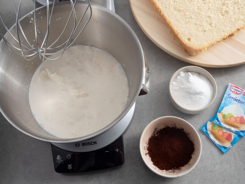 w misie robota śmietanka obok cukier puder w miseczce i kakao, obok śmietan fixy Dr. Oetkera