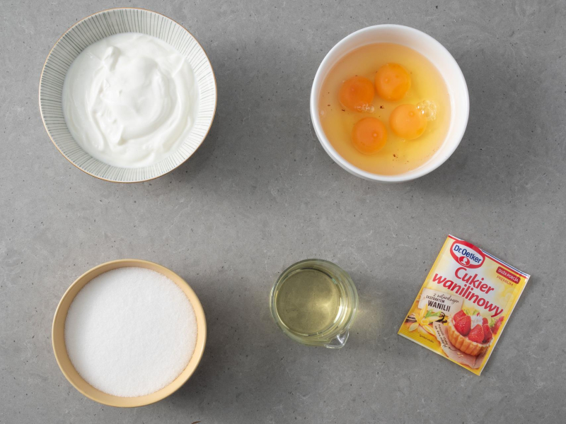 Na blacie kuchennym cukier wanilinowy, jajka, cukier, olej oraz jogurt.