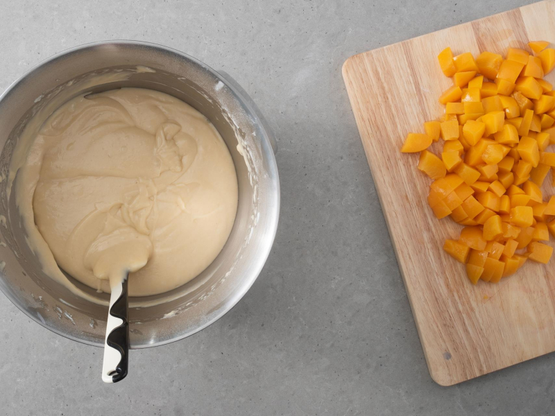 Na desce kuchennej brzoskwinie. Obok ciasto w misie.