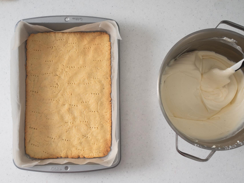 Upieczony spód na sernik z truskawkami. Obok masa twarogowa.