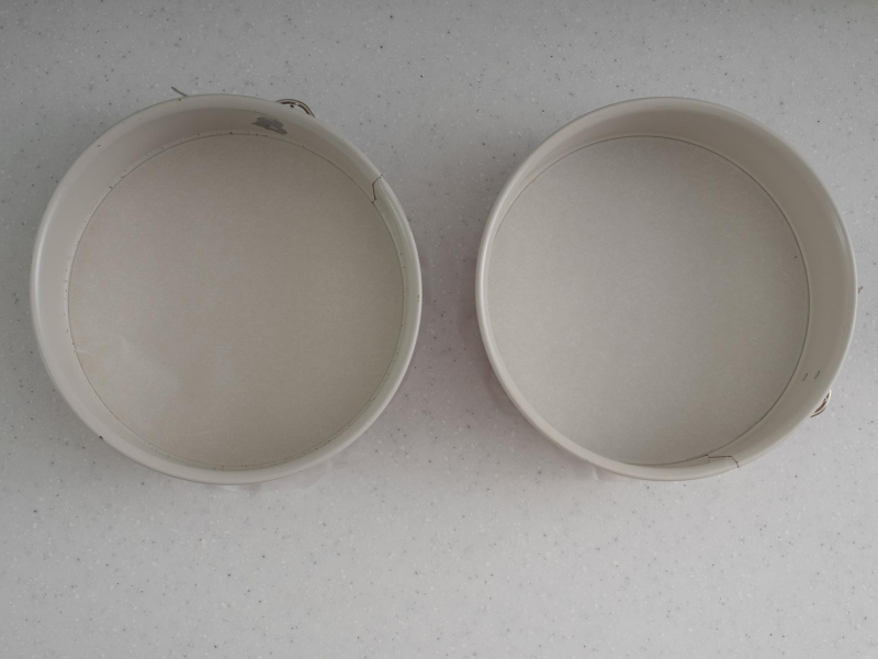 Dwie tortownice wyłożone papierem do pieczenia.